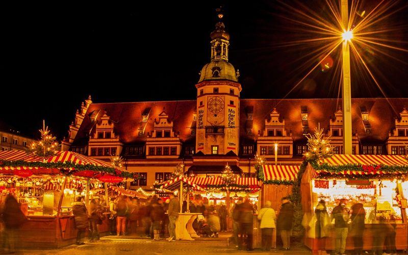 Besucher kaufen etwas an den Ständen des Leipziger Weihnachtsmarkts vor dem alten Rathaus.