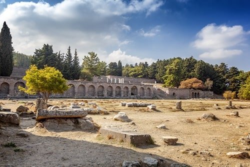 Feld mit Ruine eines antiken Krankenhauses im Hintergrund.