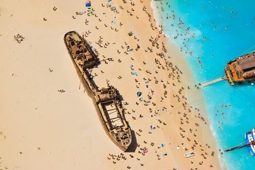Luftaufnahme von gestrandetem Schiff am Sandstrand.