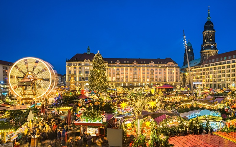 Der Altmarkt in Dresden mit vielen hell erleuchteten Marktständen und dem historischen Riesenrad.