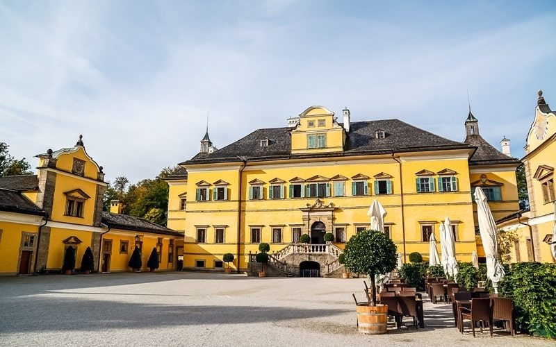 Außenansicht von Schloss Hellbrunn Salzburg mit Caféstühlen im Vordergrund