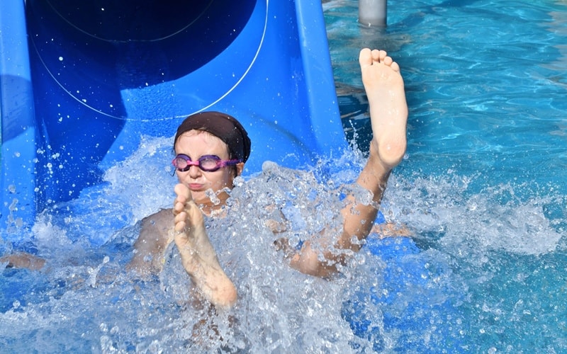 Ein Kind gleitet aus der Wasserrutsche Arriba in den Pool.