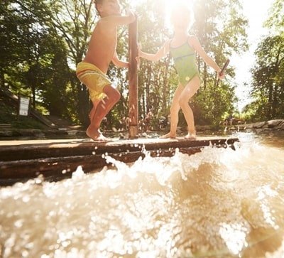 zwei Kinder spielen auf einem Floss an einem Floss auf einem Wasserspielplatz