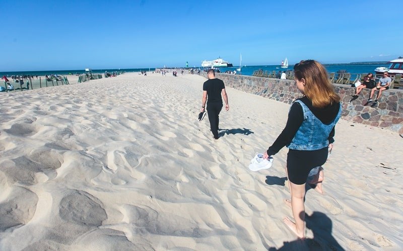 Zwei Personen laufen barfuß durch den feinen Sand im Ostseebad Warnemünde