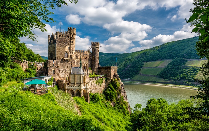 Blick auf die Burg Rheinstein und den Rhein an einem sonnigen Tag.