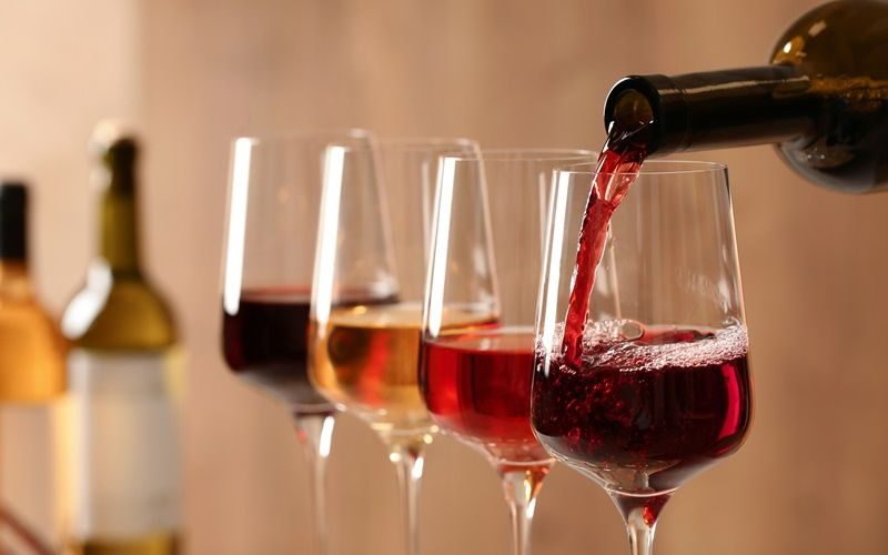Rotwein wird aus einer Flasche in ein Weinglas gegossen.